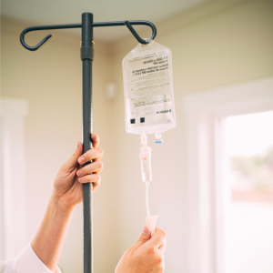Hand holding an IV drip bag, representing medical-led wellness support.